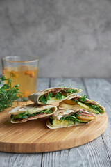 Sandwich with tortilla cheese and herbs on the wooden cutting board.
