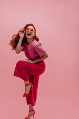 Portrait of pretty laughing caucasian young woman bending forward over pink background. Beautiful...