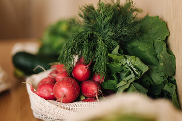 Radish in canvas grocery bag. Vegetables in reusable eco cotton bags on wooden table. Zero waste shopping concept. Plastic free items