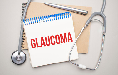 White notepad with the words glaucoma and a stethoscope on a blue background. Medical concept
