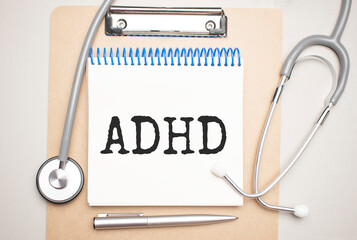 White notepad with the words adhd and a stethoscope on a blue background. Medical concept