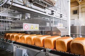 Photo sur Plexiglas Boulangerie Loafs of bread in a bakery on an automated conveyor belt