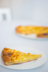 Georgian khachapuri with cheese and spices on the white plate on the white table