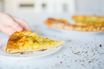 Georgian khachapuri with cheese and spices on the white plate on the white table
