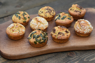 Tasty cheese mini quiches with sesame and seeds on dark wooden cutting board, muffins