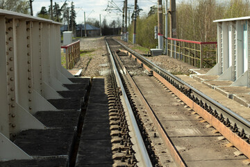Fototapeta premium The railway is one lane. The line converges in the distance. The road for the movement of the train. Rails and sleepers.