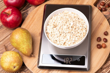 Bowl of oat flakes on the kitchen scales