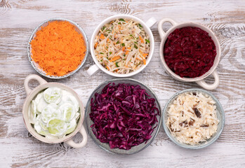 Vegetable salads in bowls on white wooden table, top view