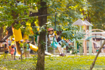The little boy goes down the zipline in the park
