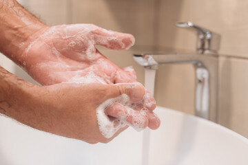 Close up of male washing hands with soap in bathroom