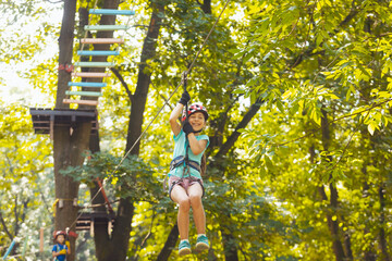 The little boy goes down the zipline in the park