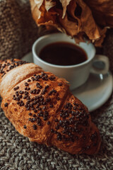 A cup of black morning coffee with a chocolate croissant. Delicious meal. Aesthetics in details. Beige and brown cozy shades