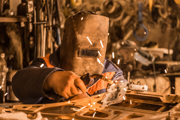 Industrial worker welder man in a protective shield is engaged in welding work and repair of the...