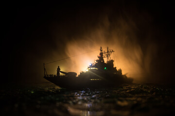 Silhouettes of a crowd standing at blurred military war ship on foggy background. Selective focus.