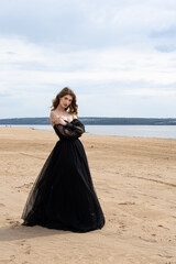 Happy young girl in a straw hat and in a black dress on the bank of the river. Thunder Sky