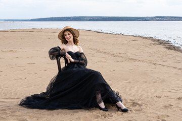 Happy young girl in black dress on the river bank