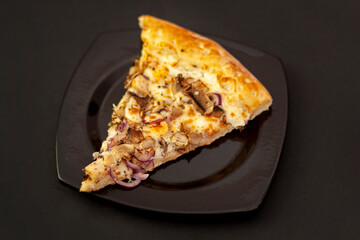 A slice of delicious pizza on a black plate. Side view