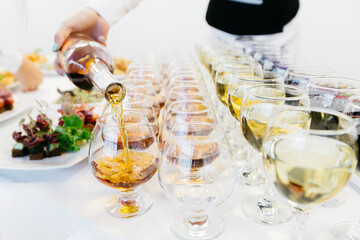 
catering service at the event. the waiter pours white wine into a glass