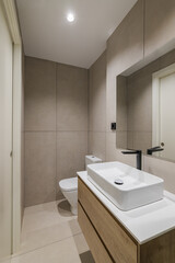 Interior of modern style bathroom in refurbished apartment. Narrow toilet with sink, black faucet and mirror.
