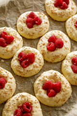 Raw raspberry sweet  buns  prepared for baking on baking paper,  close up view. Traditional yeast buns