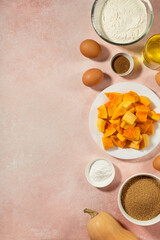 Pumpkin pie ingredients in bowls on pink table