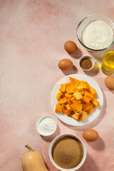 Pumpkin pie ingredients in bowls on pink table