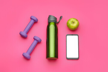 Fototapeta na wymiar Dumbbells, mobile phone, bottle of water and apple on pink background
