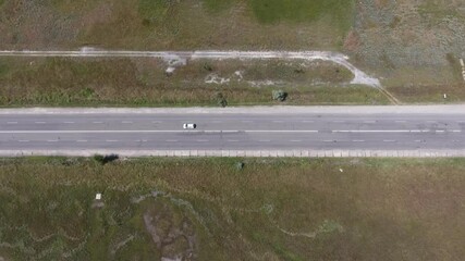 Aerial shot of a straight highway in steppe area with moving cars in the summer