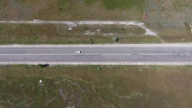 Aerial shot of a straight highway in steppe area with moving cars in the summer  