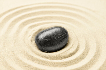 Fototapeta na wymiar Black spa stone on light sand