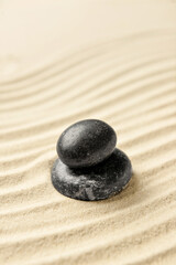 Fototapeta na wymiar Black spa stones on light sand