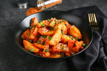 Plate with honey chilli potato on dark background