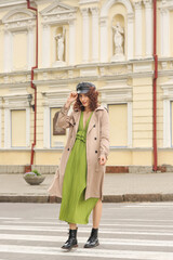 Fashionable young woman in leather cap crossing street in city