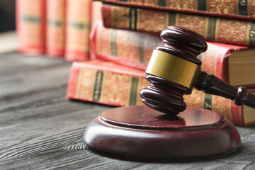 Law concept - Open law book with a wooden judges gavel on table in a courtroom or law enforcement...