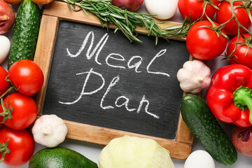Chalkboard with words MEAL PLAN and healthy products on light background