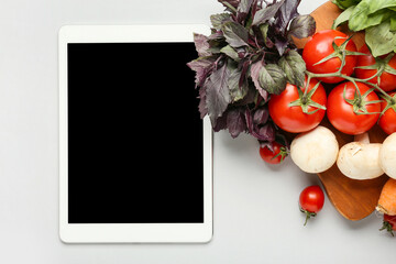 Tablet computer with healthy products on white background