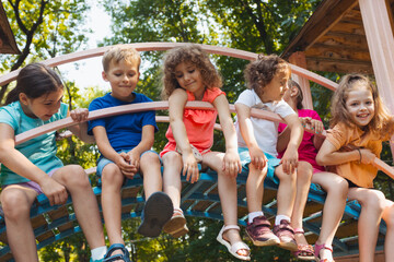 The cute kids are resting in the playground in summer