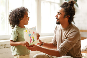 Cute little african american boy son congratulating dad with Fathers Day at home - Powered by Adobe