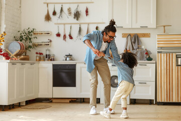 Happy african american family father and little son dancing to music in modern kitchen at home - 467797927