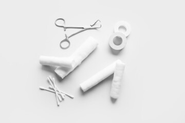 Surgical tool, bandage rolls, medical plaster and cotton buds on light background