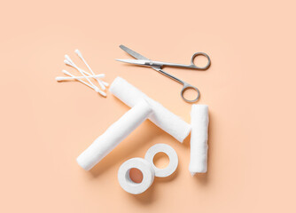 Surgical tool, cotton buds, medical plaster and bandage rolls on color background