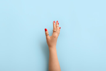 Female hand with beautiful manicure and stylish rings on color background