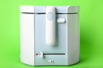 Modern deep fryer on color background