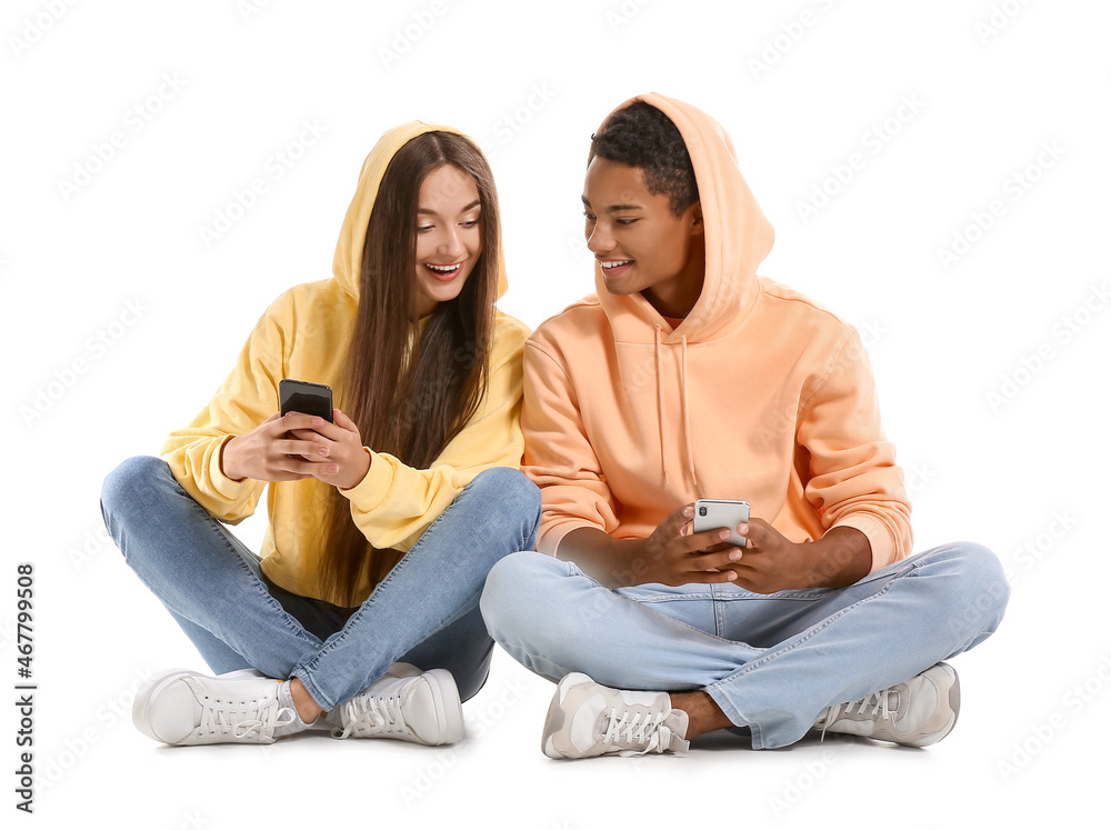 Canvas Prints Stylish young couple using mobile phones on white background