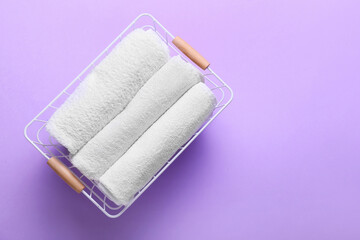 Basket with clean towels on lilac background