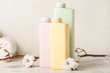Bottles of cosmetic products and cotton branch on light background