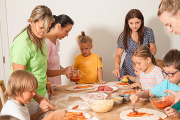 Group of mothers with children make pizza