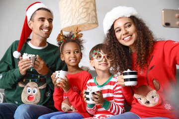 Happy family with cups of hot cocoa taking selfie at home on Christmas eve