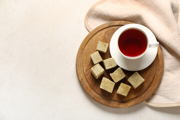 Board with tasty hojicha marshmallows and cup of tea on light background
