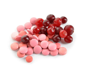 Heap of cranberry pills and berries on white background
